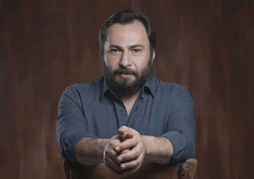 Oyuncu Mustafa Kırantepe bir sandalyeye dayanarak objektife bakarken