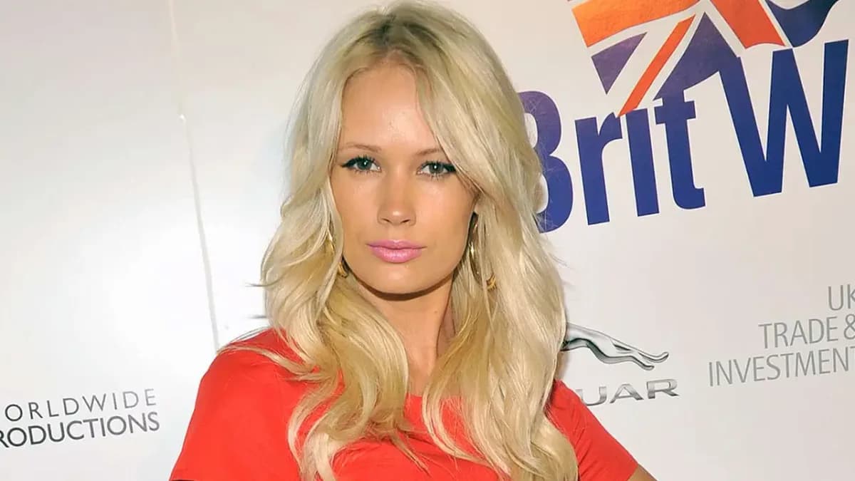 İngiliz şarkıcı Lauren Bennett sarı saçları ve kırmızı elbisesiyle bir etkinlik panosu önünde poz veriyor