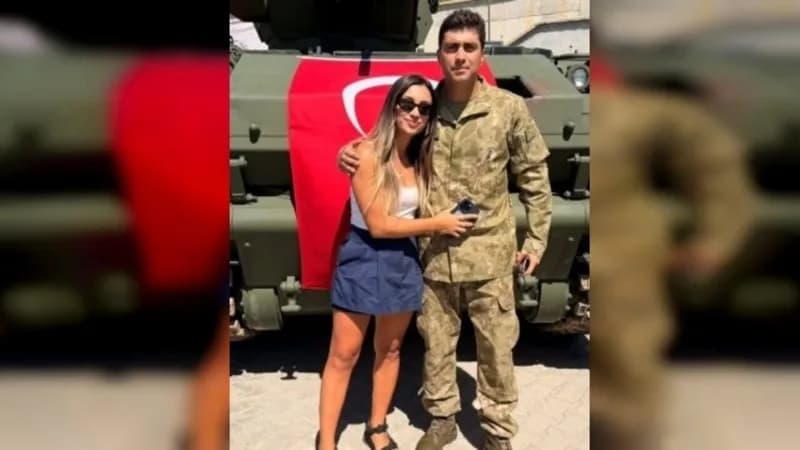 Askeri kıyafetli genç bir erkek ve yanındaki kadın Türk bayrağı asılı zırhlı araç önünde