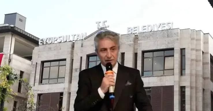 Eyüpsultan Belediyesi binası önünde elinde mikrofonla konuşan takım elbiseli bir kişi