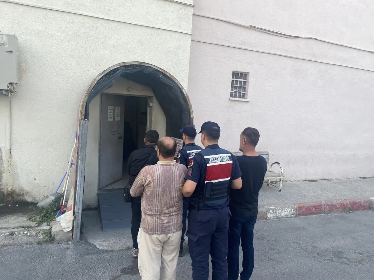 Jandarma ekibi gözaltına alınan kişileri bir binanın kemerli kapısından içeri götürüyor