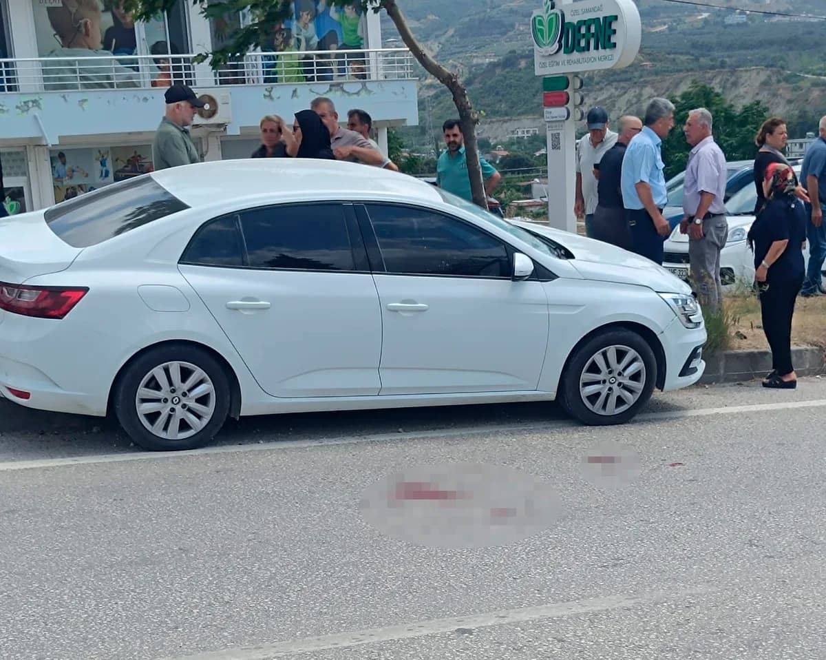 Yol kenarında duran beyaz otomobil ve çevresinde toplanan kalabalık