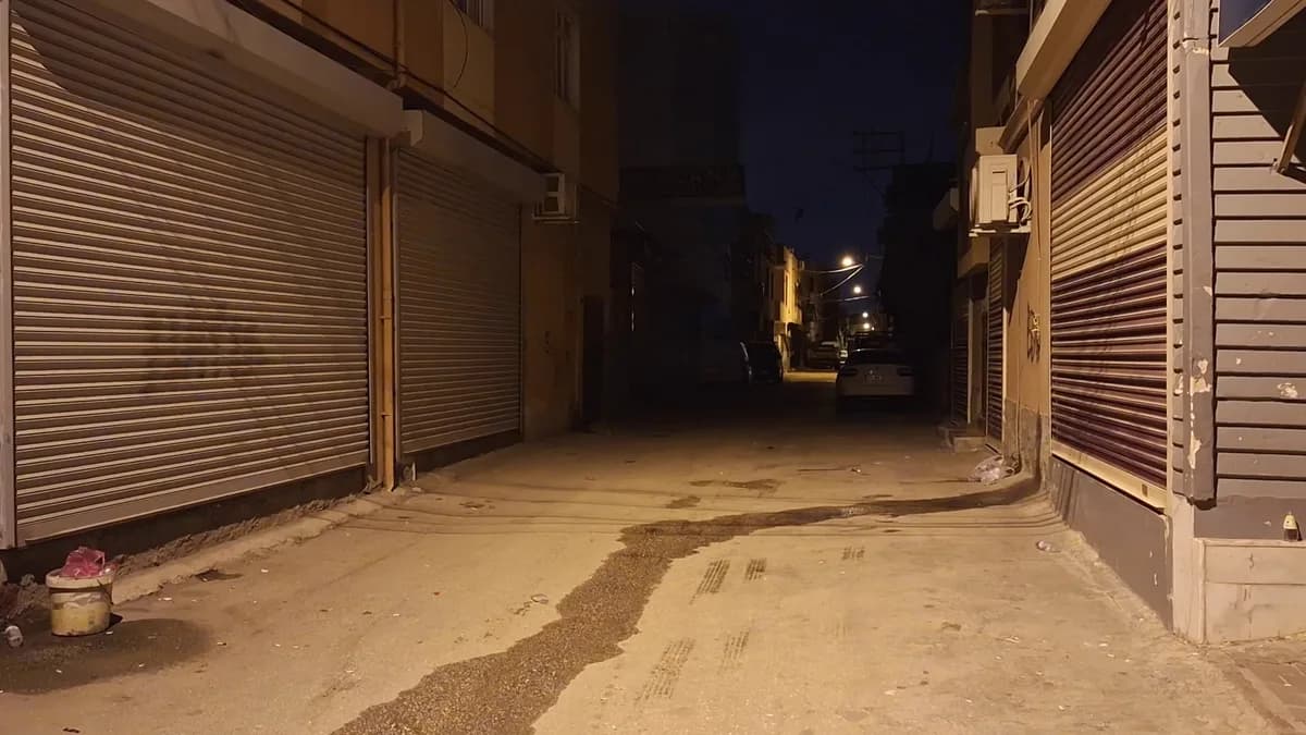 Gece boş bir sokakta kepenkleri kapalı dükkanlar ve tenha cadde
