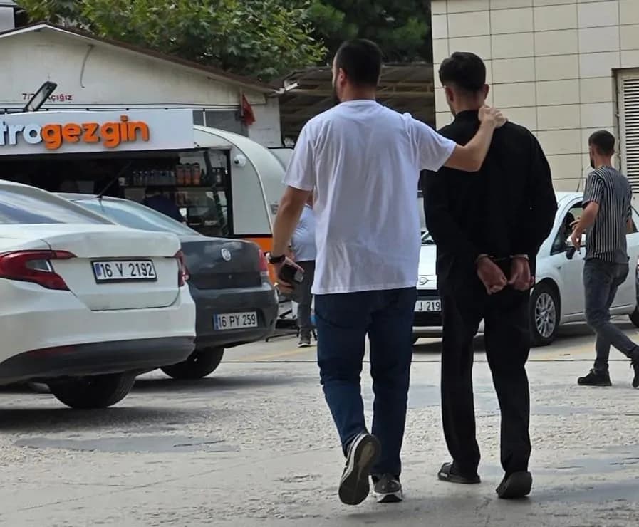 Elleri kelepçeli siyah giyimli şüpheli sivil polis eşliğinde götürülüyor