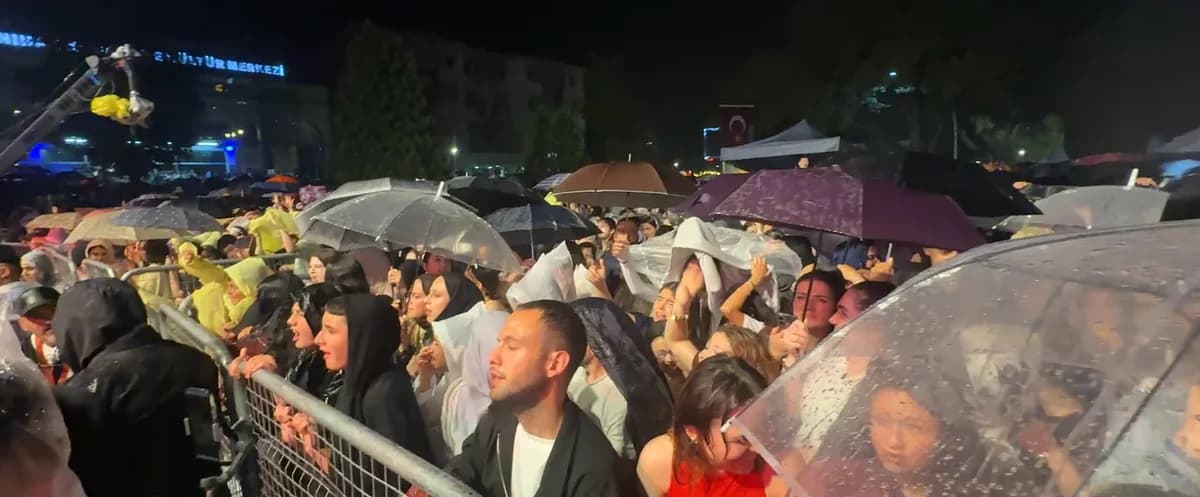 Yağmur altında şemsiyeli kalabalık gece konseri izliyor