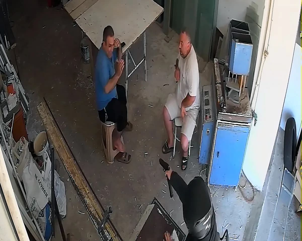 İş yerinde tabure ve sandalyede oturan iki adama silahla yaklaşan kasklı saldırganın güvenlik kamerası görüntüsü