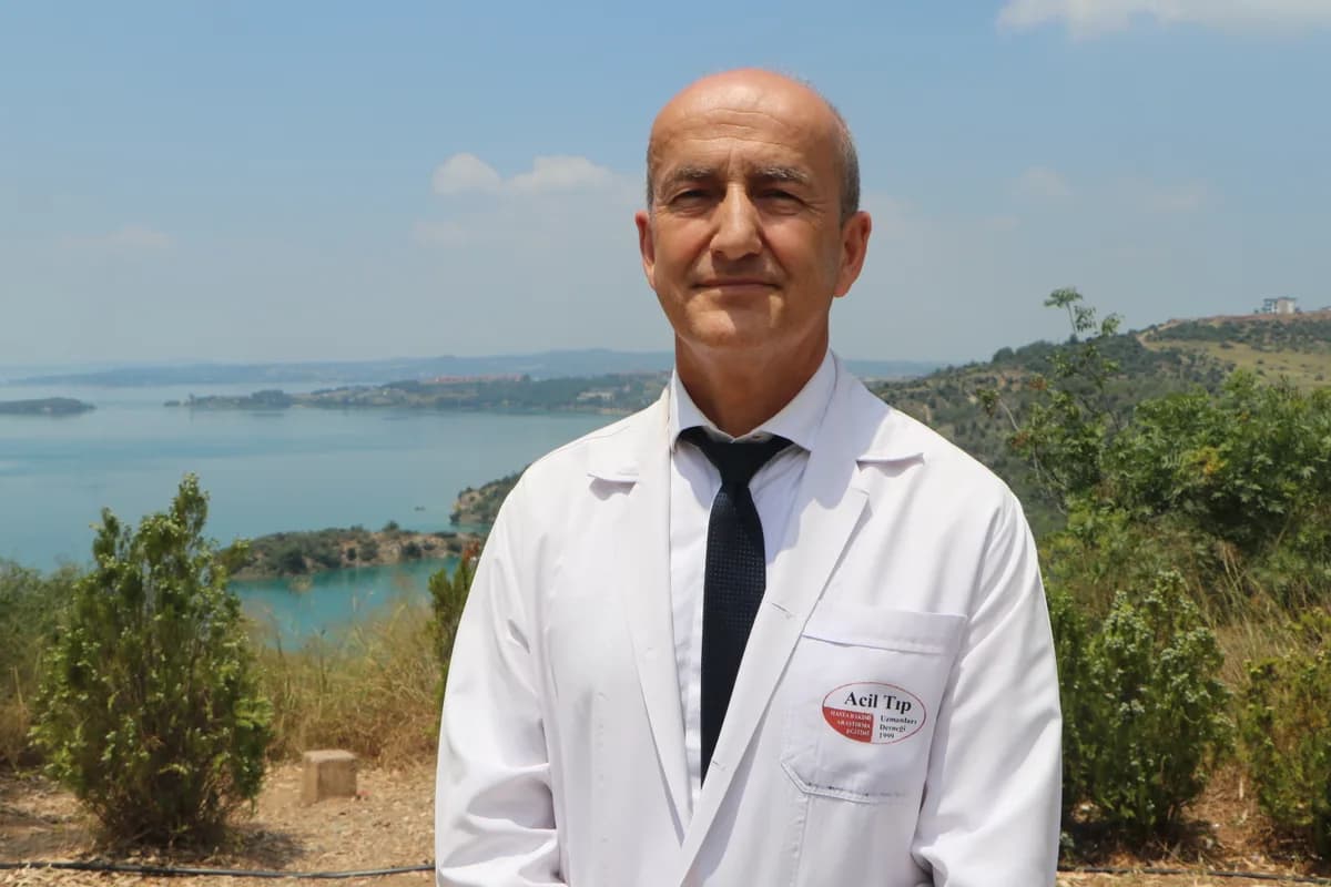 Acil Tıp logolu beyaz önlük giyen doktor göl manzarası önünde