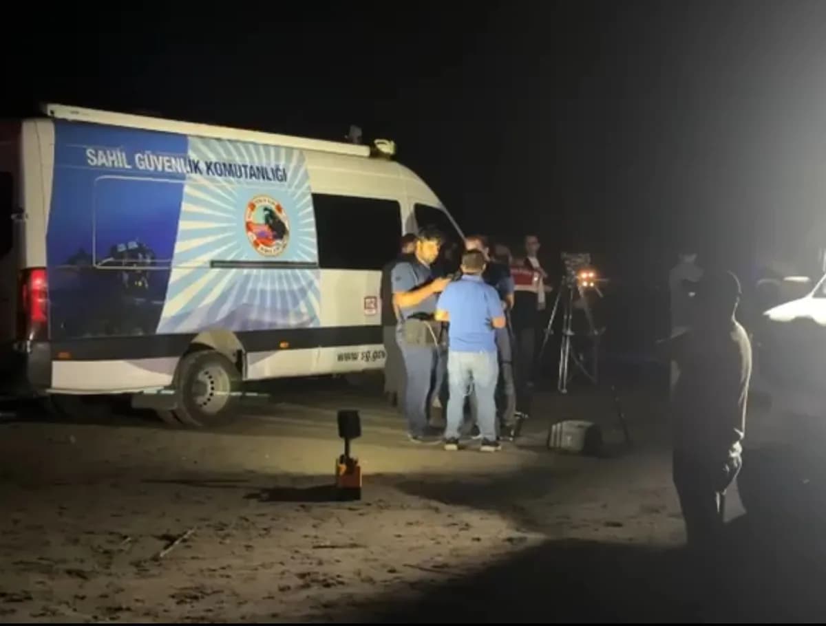Gece sahilde park halindeki Sahil Güvenlik Komutanlığı aracının önünde toplanan arama kurtarma ekipleri ve görevliler