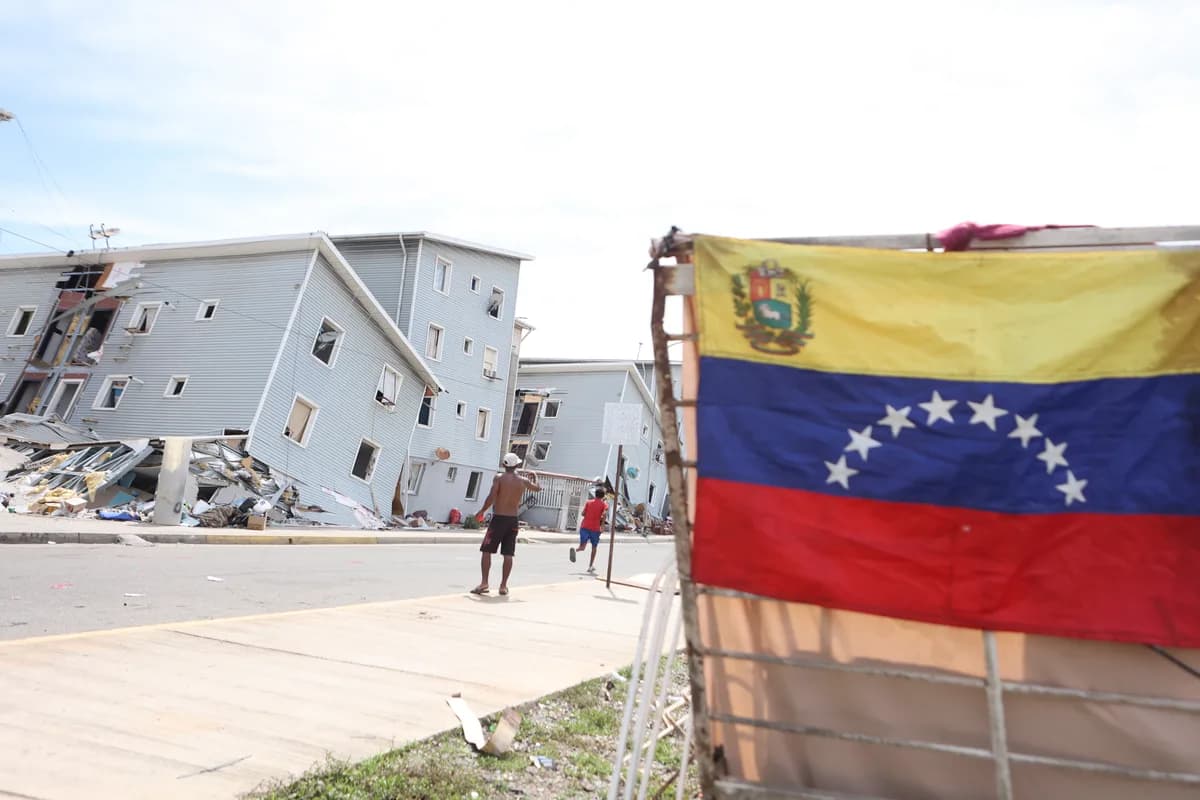 Yıkılmış binaların önünde Venezuela bayrağı ve enkaz arasında yürüyen kişiler